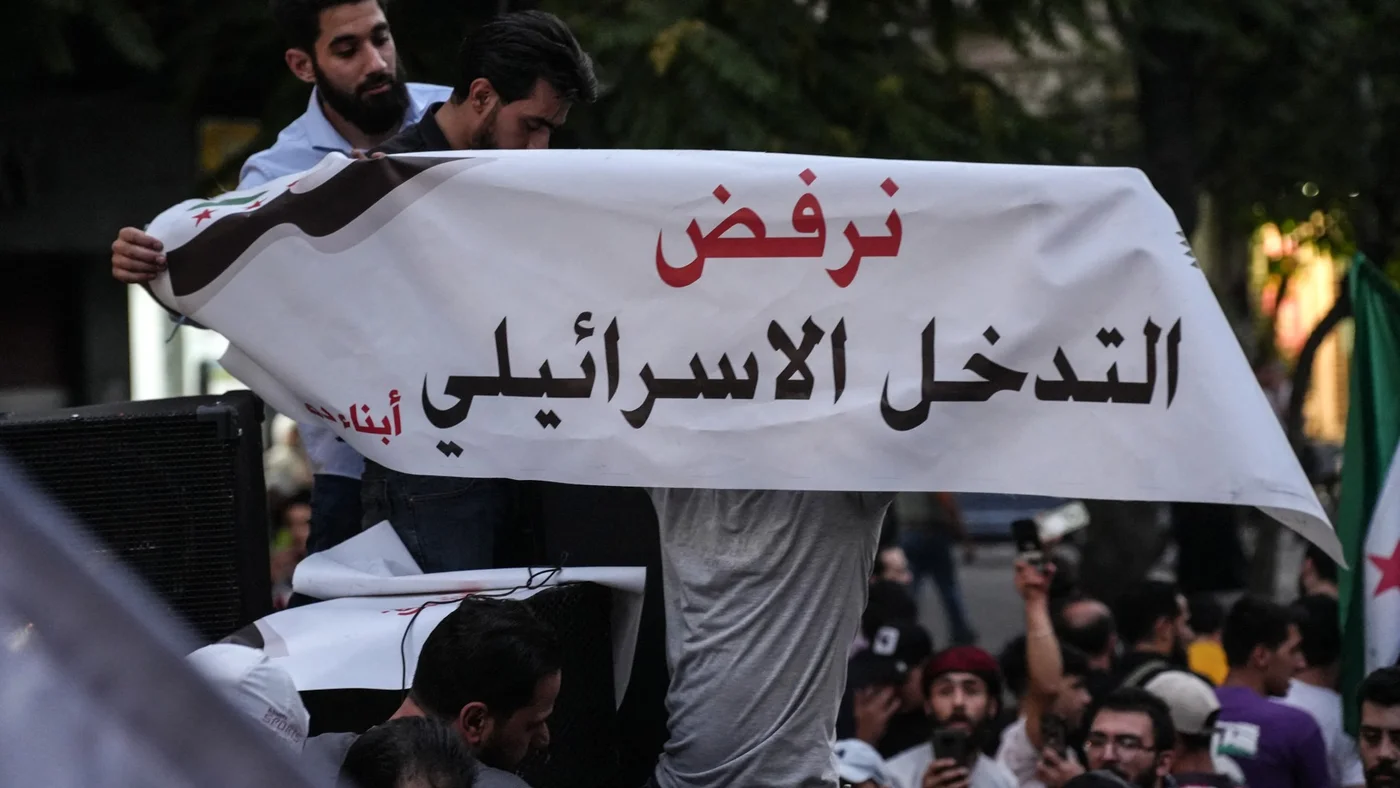 Men carry a banner during a demonstration against Israeli intervention in Syria, in Damascus on July 16, 2025-afp.jpg
