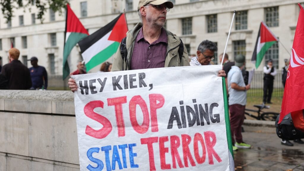 A Maccabi Tel Aviv elleni vita felfedte Starmer álsztoriját a népirtásban való összejátszásról. 5 A protester holds a banner with a message to Britains Prime Minister Kier Starmer during a vigil for journalists killed in Gaza outside Downing Street in central London on August 27 2025 afp